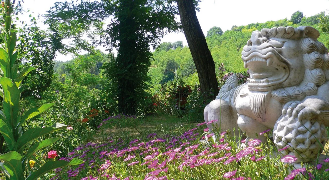 Scultura in pietra tra i fiori del giardino